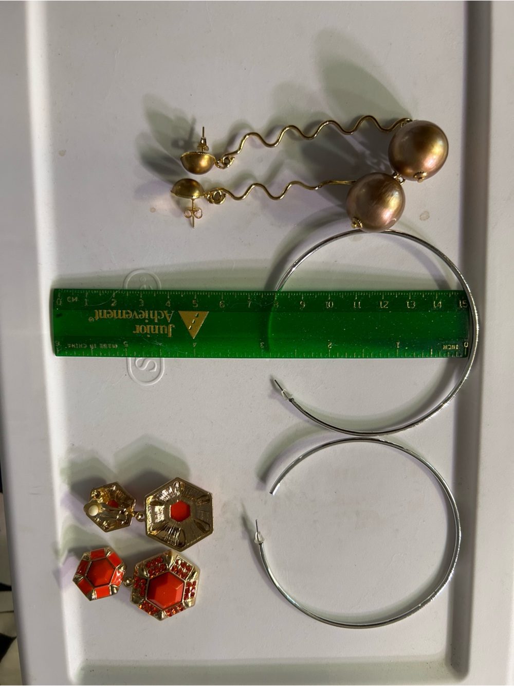 Bundle of big silver color hoops, long gold color earrings and orange clips